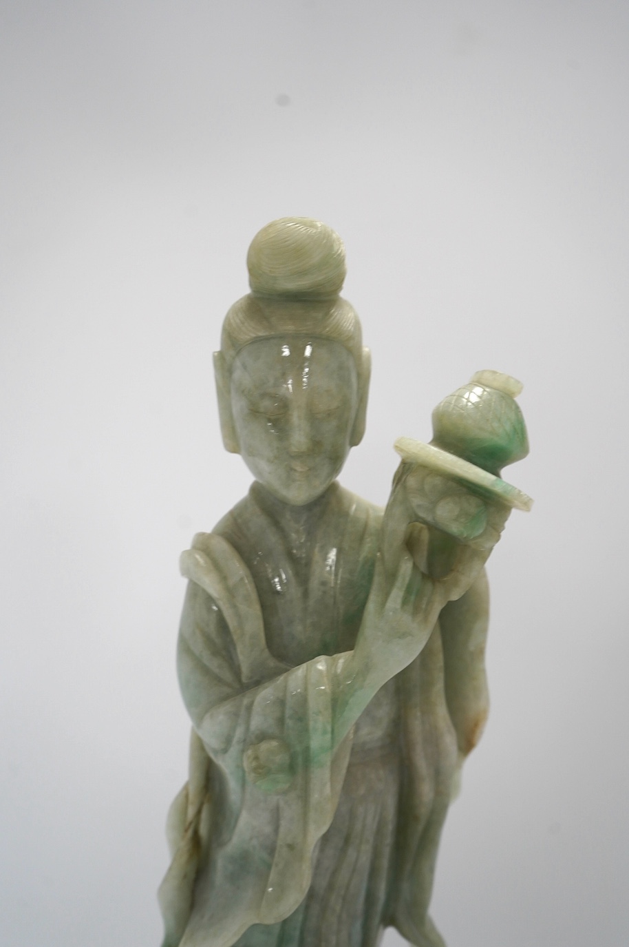 A Chinese jadeite carving of Guanyin, on associated hardwood stand, 38cm high. Condition - fair